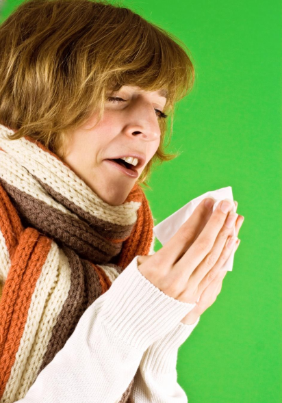 A woman on the verge of sneezing with a tissue in her hand.